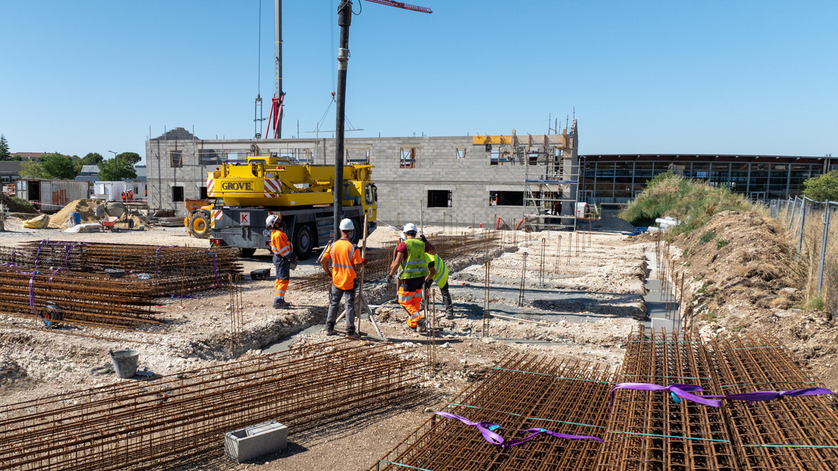 Construction workers preparing foundation with crane and rebar
